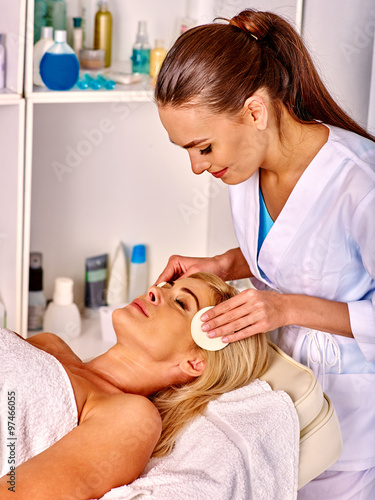 Woman middle-aged take face cleaning in spa salon.