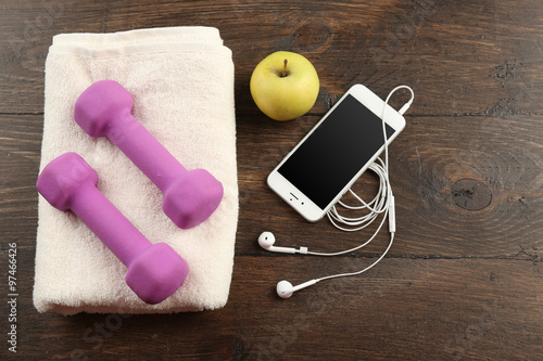 Sport equipment, towel and smart phone on wooden background