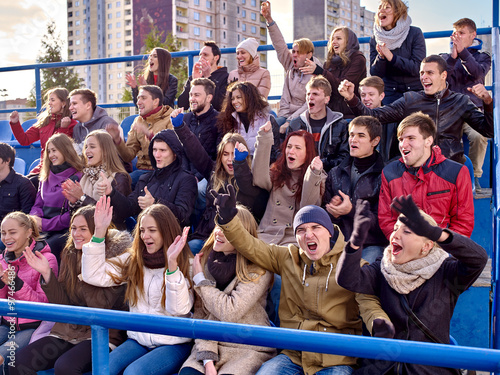 Sport fans clapping and singing on tribunes. photo