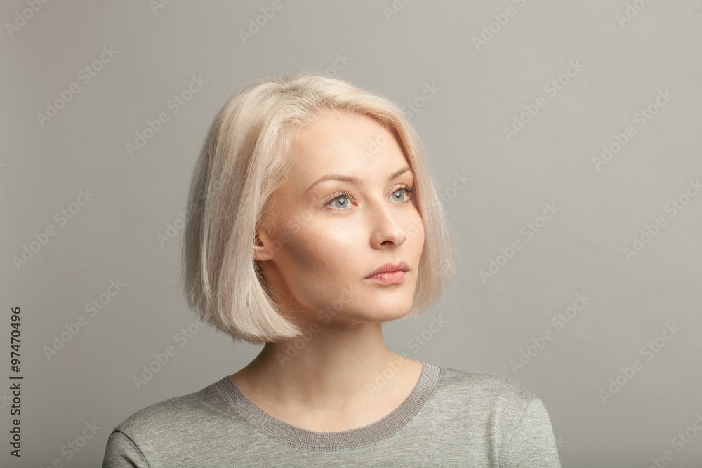 Naklejka premium blonde woman in gray t-shirt looking right on gray background