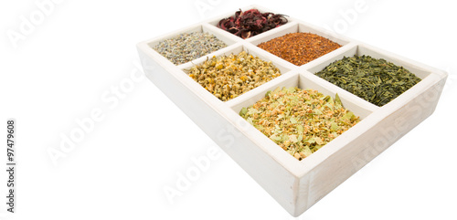 Dried herbal tea leaves, lavender, rooibos, chamomile, linden flower, hibiscus, Japanese green tea in white wooden box over white background