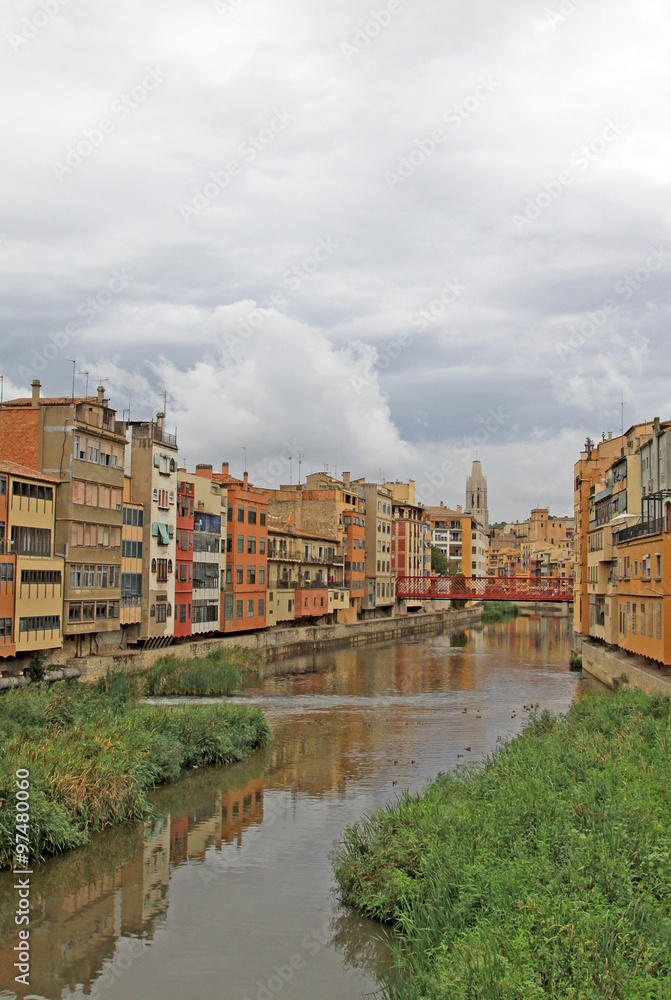 GIRONA, SPAIN - AUGUST 30, 2012: View of the old town with colorful houses on the bank of the river Onyar GIRONA, SPAIN - AUGUST 30, 2012: View of the old town with colorful houses on the bank of the river Onyar