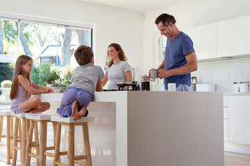 family in kitchen, parents preparing breakfast