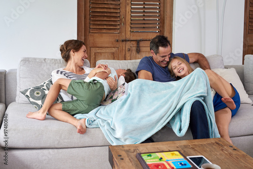 Billede på lærred Playful kids jumping parents sitting on the sofa