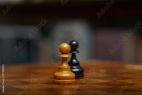 Chess. Chess on the chessboard. Two pawns. Confrontation. Winning the fight.