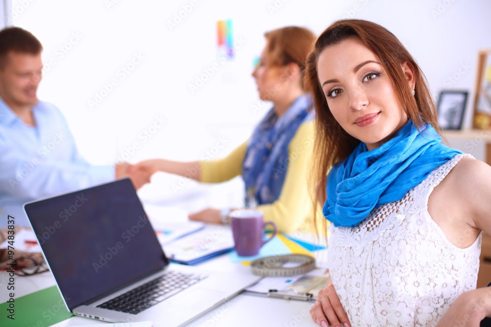 Portrait of attractive designers sitting on desk in office Portrait of attractive designers sitting on desk in office