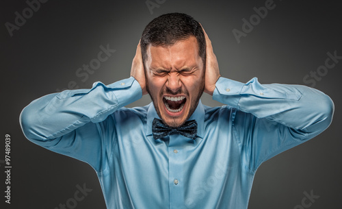 Portrait angry upset young man in blue shirt, butterfly tie 