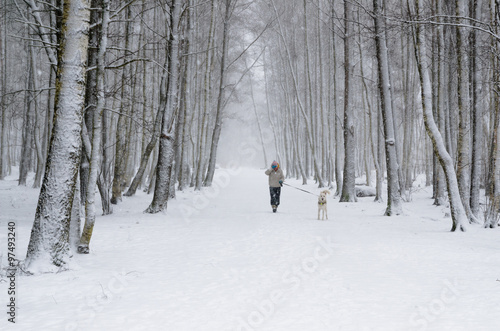 Woman with dog on a snowy winter alley