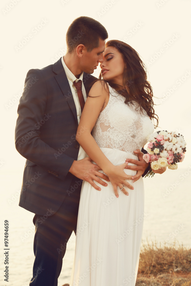 beautiful groom and bride in wedding clothes posing on sea coast beautiful groom and bride in wedding clothes posing on sea coast