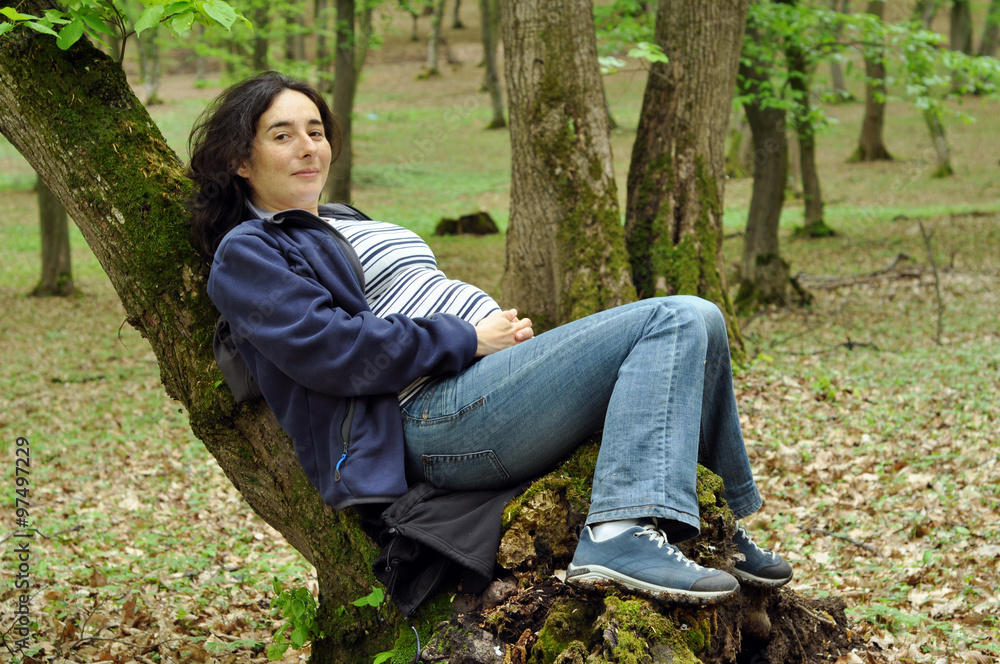 Pregnant woman relaxing on a tree trunk Pregnant woman relaxing on a tree trunk