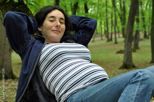 Calm pregnant woman relaxing in the forest