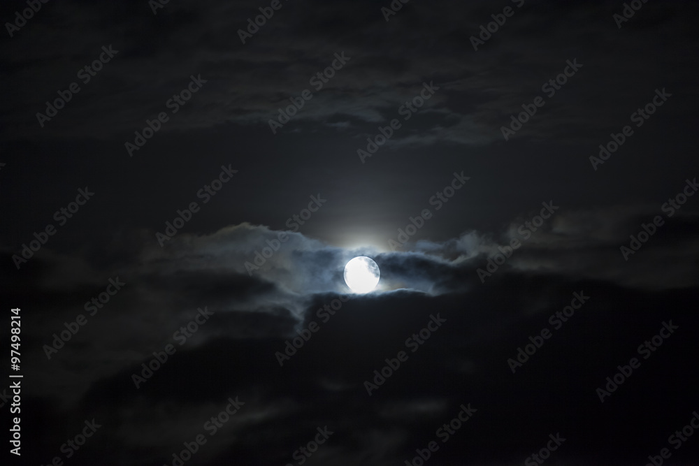 Fototapeta premium Moon shining in cloudy night sky.