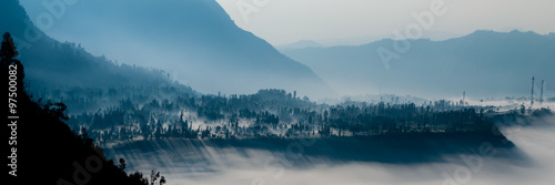 Steep black mountain silhouette in front of thick Fog Sheet