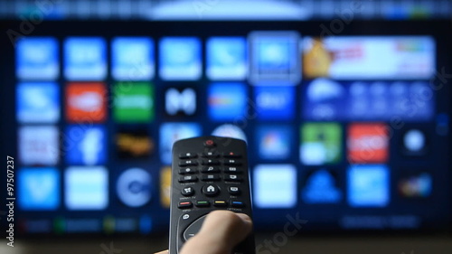 Smart tv and hand pressing remote control. photo