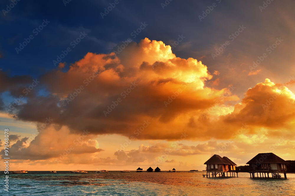 Sunrise over water bungalows on a cloudy day at the end of rainy season in Maldives. Sunrise over water bungalows on a cloudy day at the end of rainy season in Maldives.