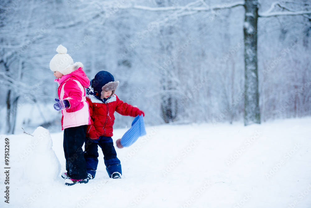 Little boy and girl molding a snowman Little boy and girl molding a snowman