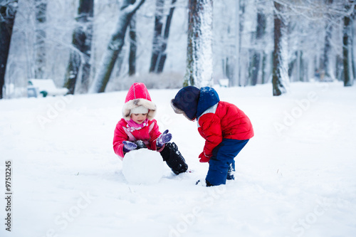 Little boy and girl molding a snowman