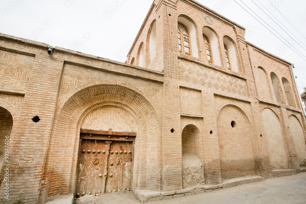 Stone house in the Iranian style masonry and wooden door in a narrow street of Middle East