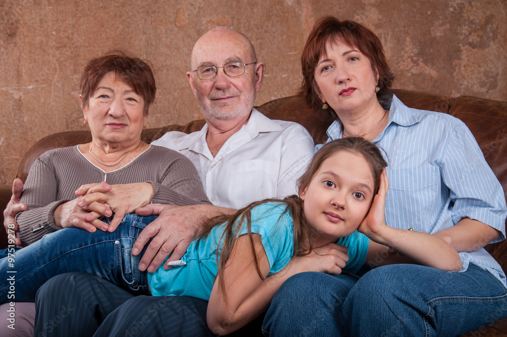 Большая семья с бабушкой дедушкой, мамой и ребенком сидят на диване