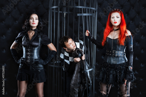 Fotografi Two girls mistress dominate man in the cell.