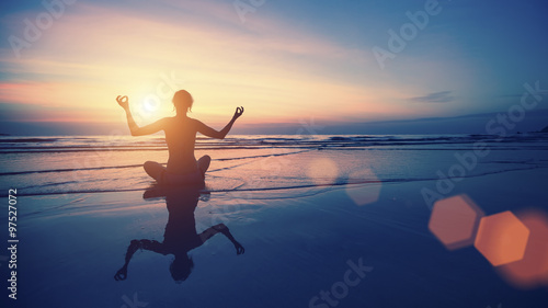 Silhouette meditation woman on the background of the sea and sunset. Yoga and healthy lifestyle.