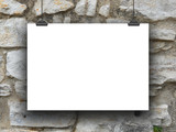 One hanged horizontal paper sheet frame with clips on medieval stone wall background 