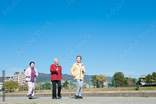 青空を背景に歩いている3人のアジア人高齢者