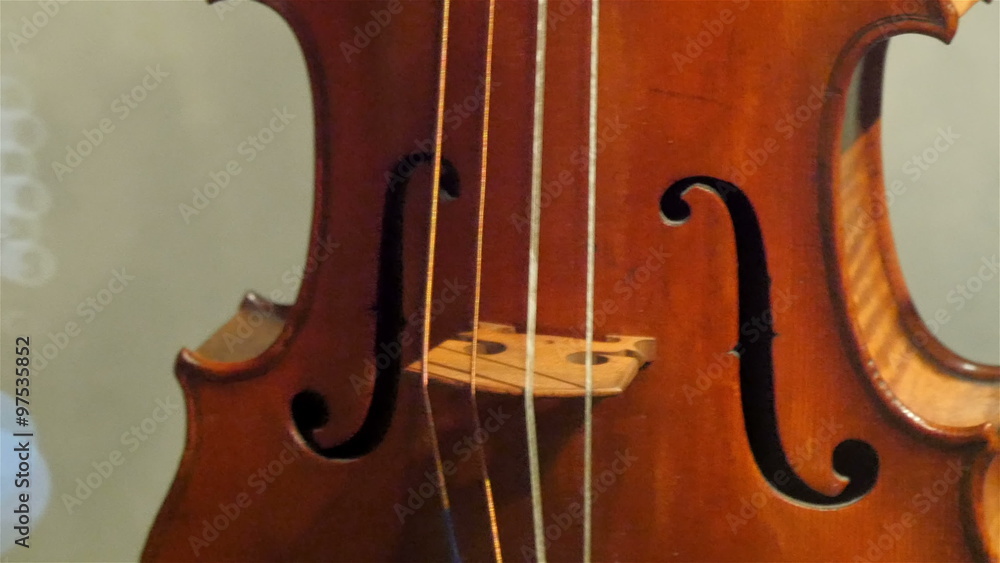 The four-stringed violin on display. The small brown violin is standing on the corner of the room The four-stringed violin on display. The small brown violin is standing on the corner of the room