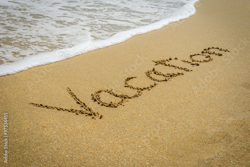 Word vacation on the beach sand - vacation and travel concept