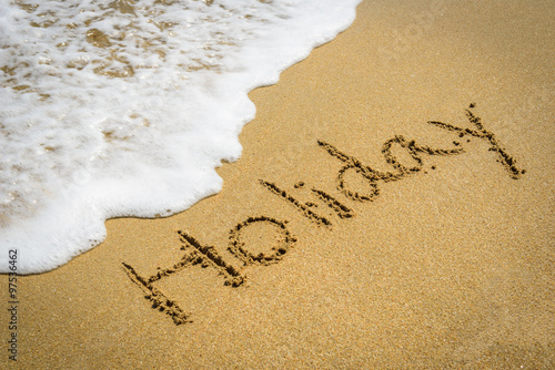 Word holiday on the beach sand - vacation and travel concept