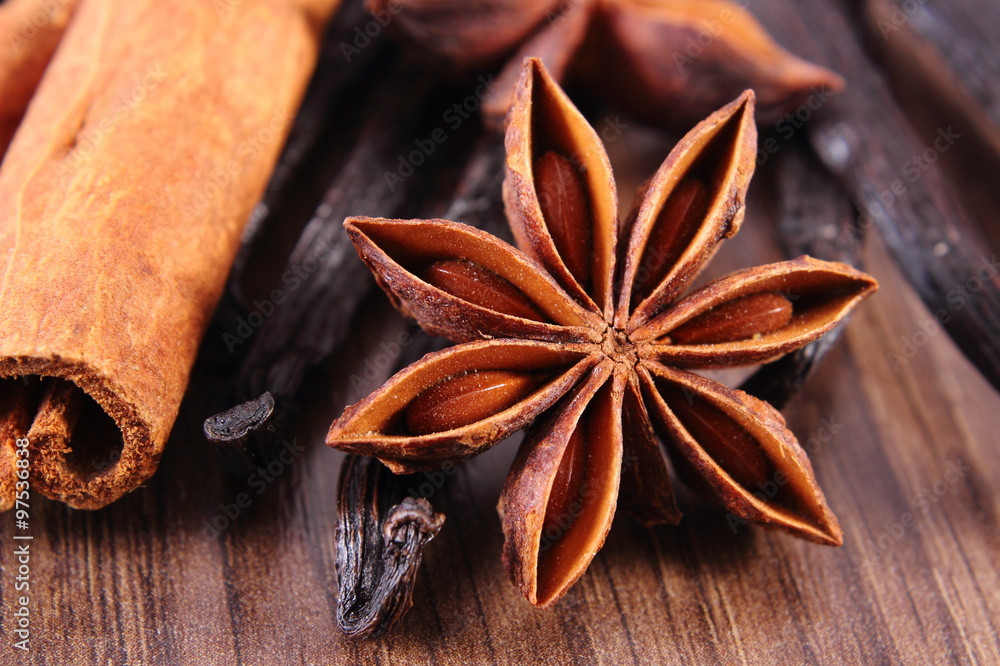 Closeup of star anise, fragrant vanilla and cinnamon on wooden surface plank Closeup of star anise, fragrant vanilla and cinnamon on wooden surface plank