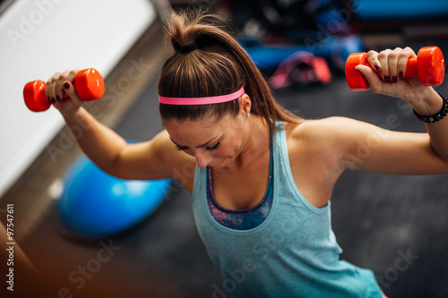 Woman lifting weights and working on her shoulders at the gym photo