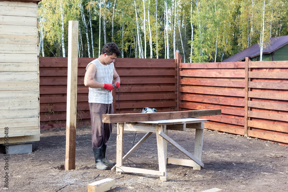 man turns on power circular saw for cutting beams man turns on power circular saw for cutting beams