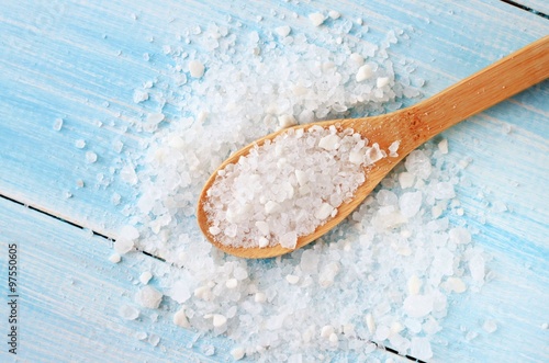 Sea salt grind on wooden light blue shabby table wooden spoon. Kitchen and cosmetic healthy usage.