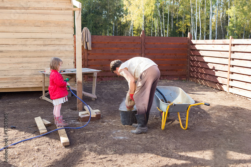 Dad and daughter prepare cement mixture in the bucket
