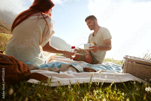 Young couple on picnic drinking wine