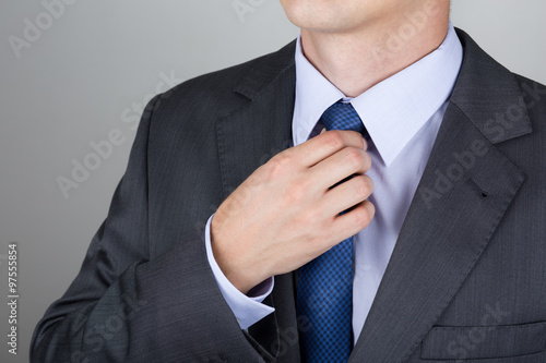 Well dressed business man adjusting the necktie