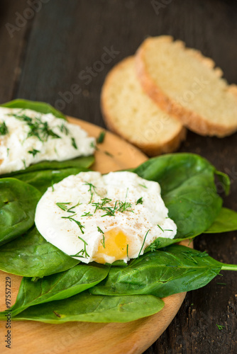 Poached egg on a piece of bread with spinach on the table