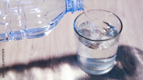 bottiglia di plastica trasparente versa bevanda acqua nel bicchiere sul tavolo photo