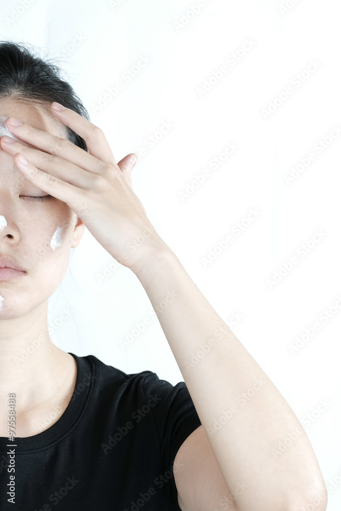 Asian girl applying cream lotion on face, isolated on white background Asian girl applying cream lotion on face, isolated on white background