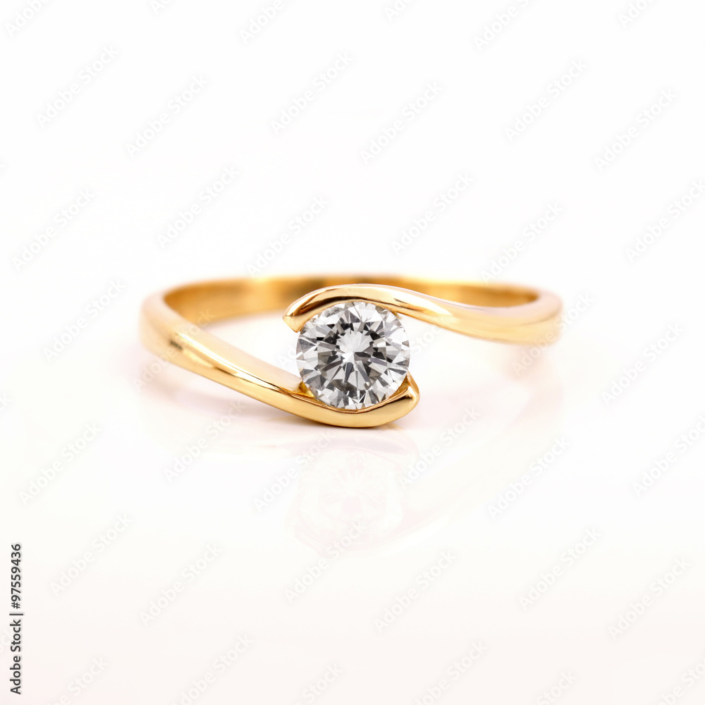 Gold engagement ring with a diamond on a white background - obrazy, fototapety, plakaty 