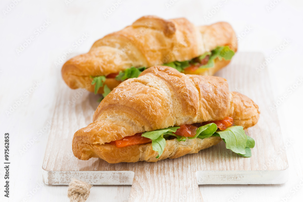 fresh croissant stuffed with fish and arugula on wooden board fresh croissant stuffed with fish and arugula on wooden board
