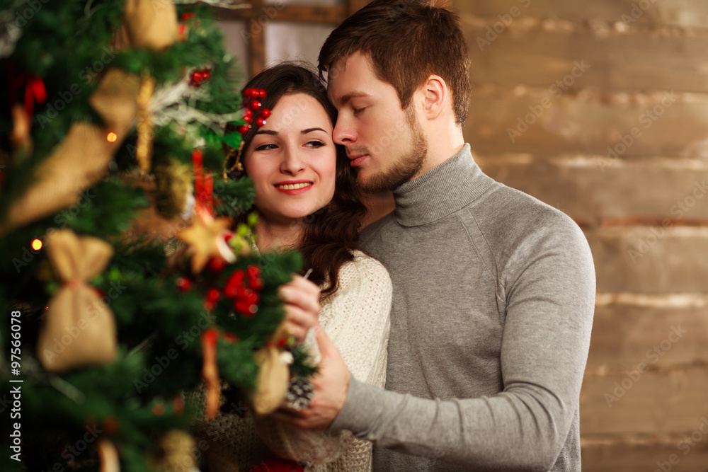 Young couple in love decorates a Christmas tree at home Young couple in love decorates a Christmas tree at home