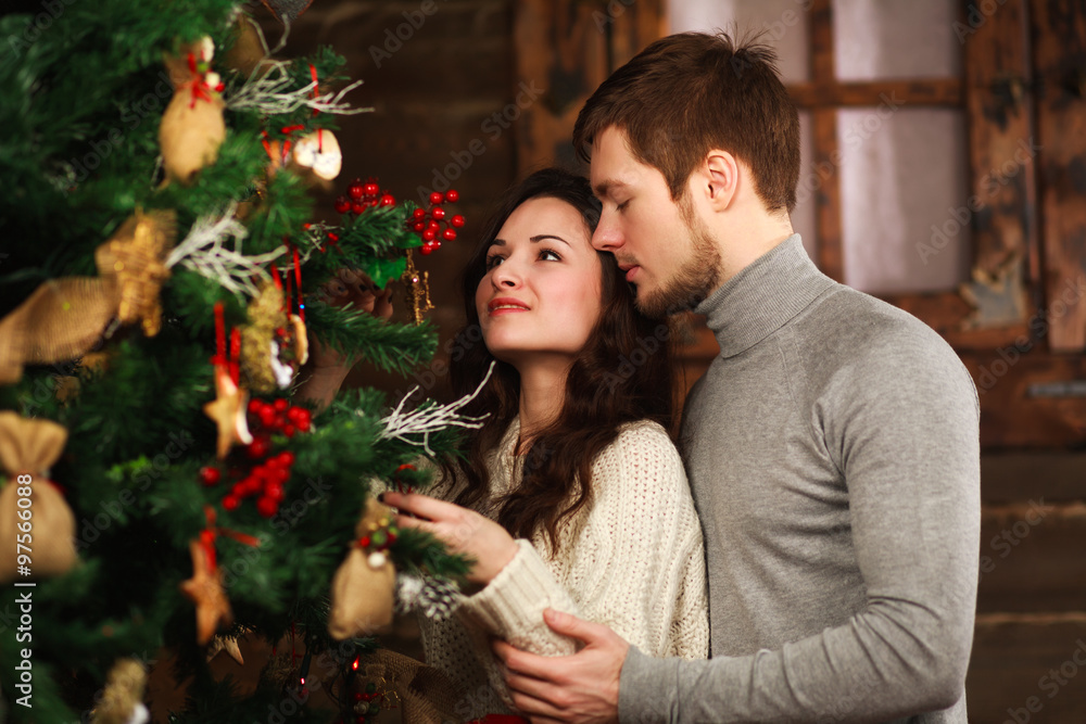 Young couple in love decorates a Christmas tree at home Young couple in love decorates a Christmas tree at home