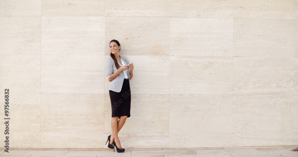 Stylish businesswoman standing against a wall Stylish businesswoman standing against a wall