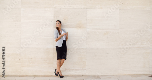 Stylish businesswoman standing against a wall
