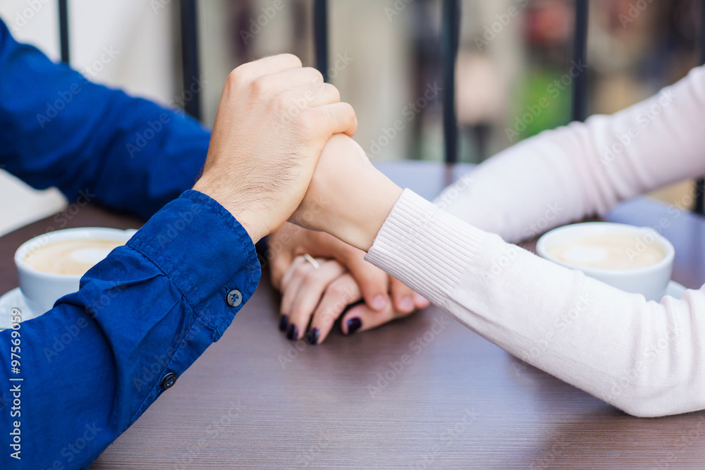 Hands of happy loving couple in a restaurant