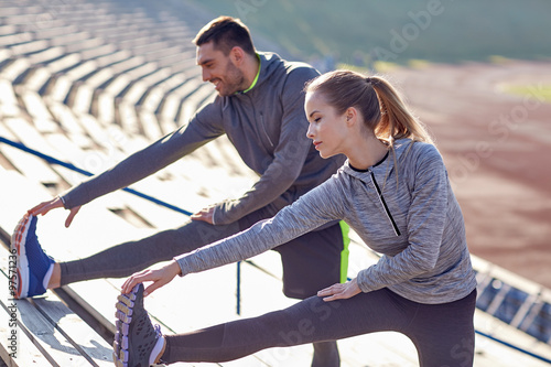 couple stretching leg on stands of stadium