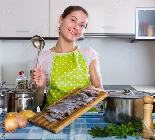 Woman preparing small fish indoors. photo