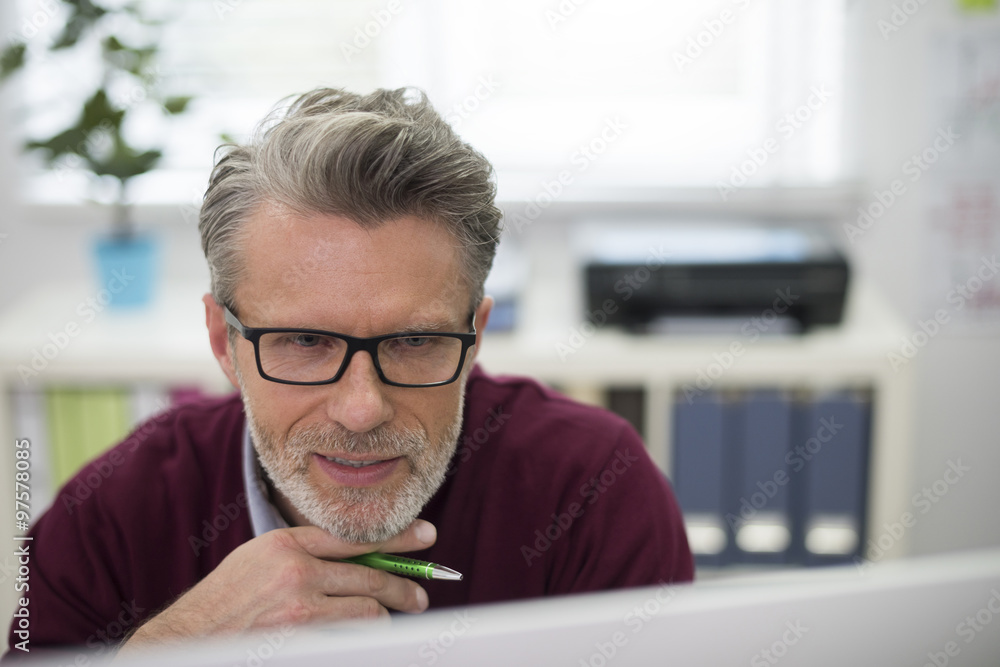 Watchful man using computer at the office Watchful man using computer at the office